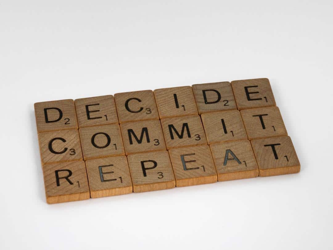 Scrabble tiles spelling out DECIDE, COMMIT, REPEAT representing decision-making as one of the stages of buying intent.
